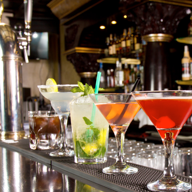 Diverse cocktails staan naast elkaar op een bar