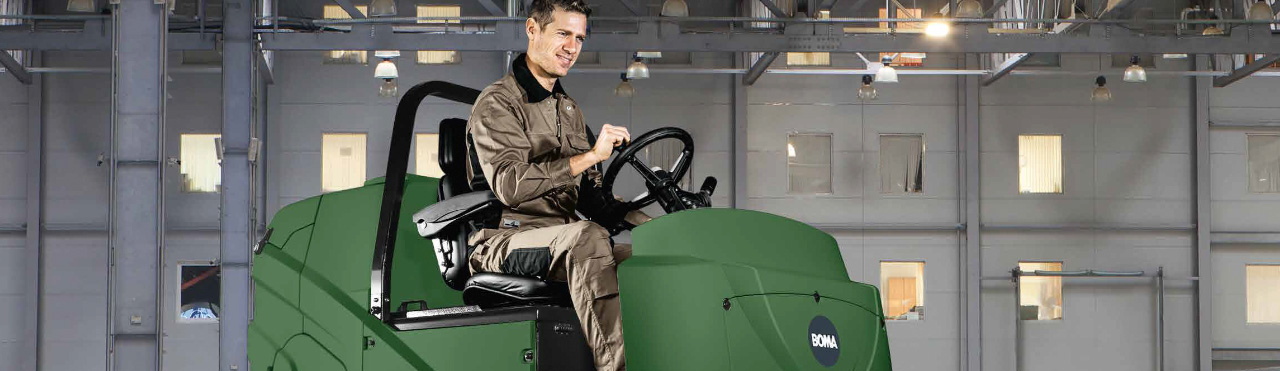 schoonmaker maakt de vloer schoon met een schoonmaakmachine in een grote hal